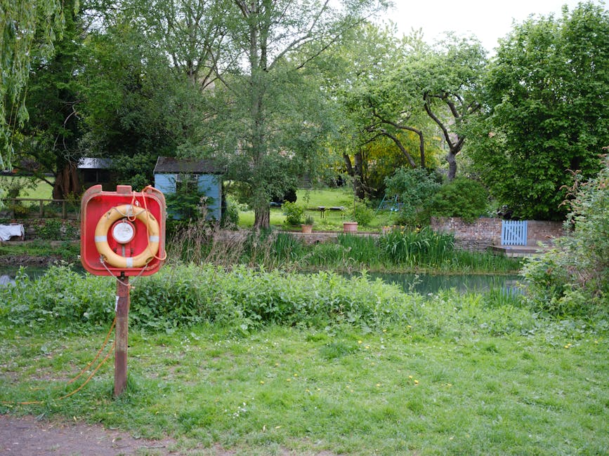 A serene garden scene in Gladstone Park featuring a lush, well-maintained lawn with neatly trimmed grass, bordered by dense greenery including bushes and trees with fresh green leaves. In the foregrou